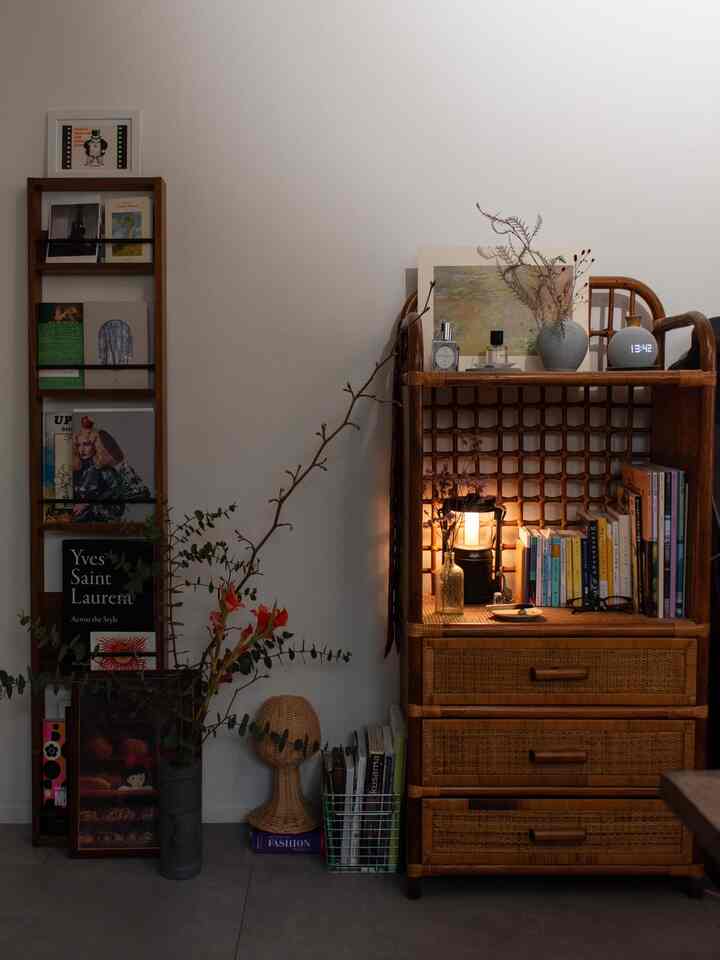 Natural color studio apartment featuring a rattan cabinet with art books and a vase lamp, creating a warm atmosphere