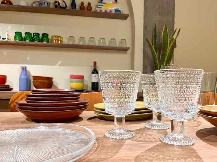 透明なカステヘルミのグラスとカラフルな皿が置かれた温かみのあるキッチンのインテリア