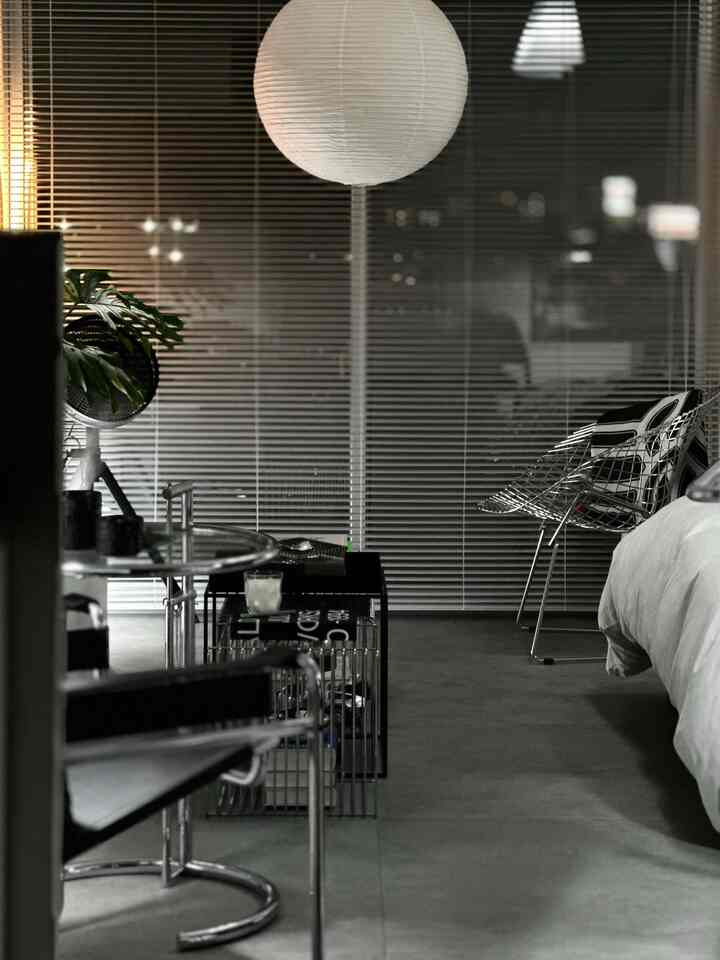 Modern natural-colored bedroom featuring chrome metal furniture and a large spherical pendant light creating a sleek atmosphere