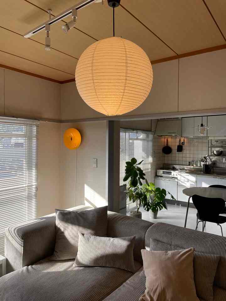 Natural brown-toned living room connected to kitchen, featuring a large pendant light centrally placed with cozy atmosphere