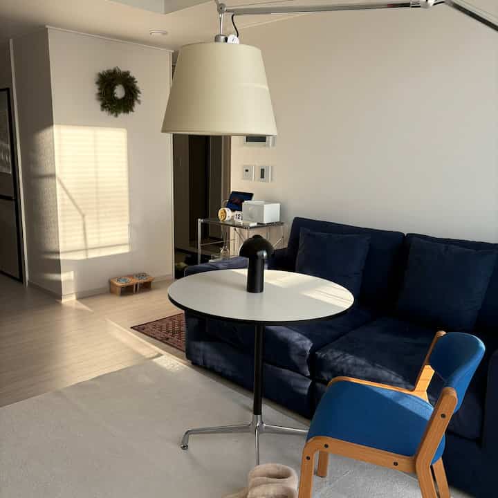 White and navy toned living room featuring a sofa, round table, and armchair arranged in a simple and minimal interior