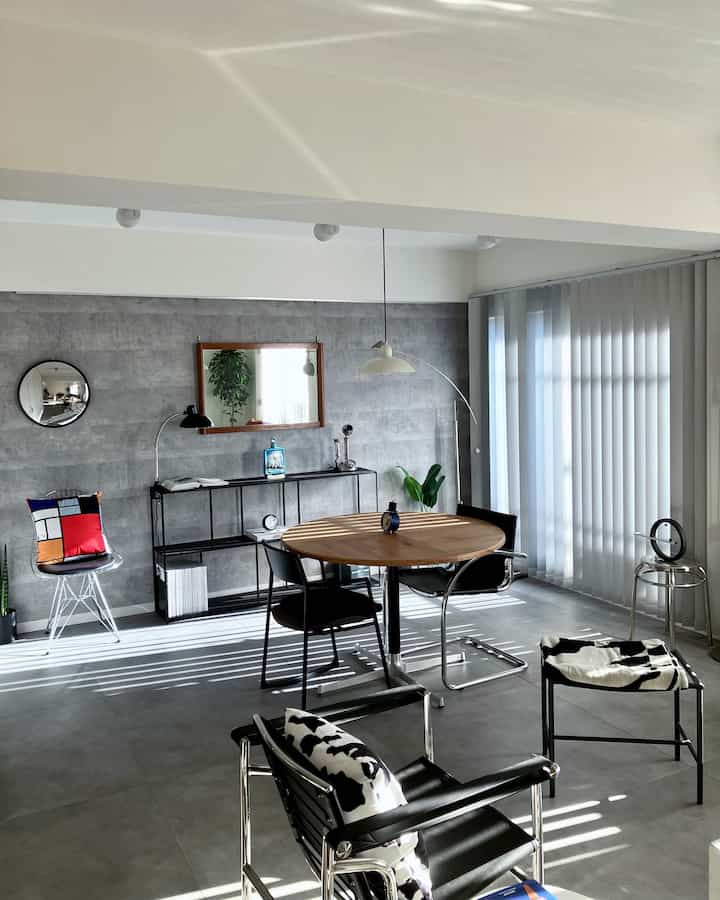 グレーのコンクリート壁と金属家具が調和したミッドセンチュリーモダンとインダストリアルスタイルのダイニングルーム