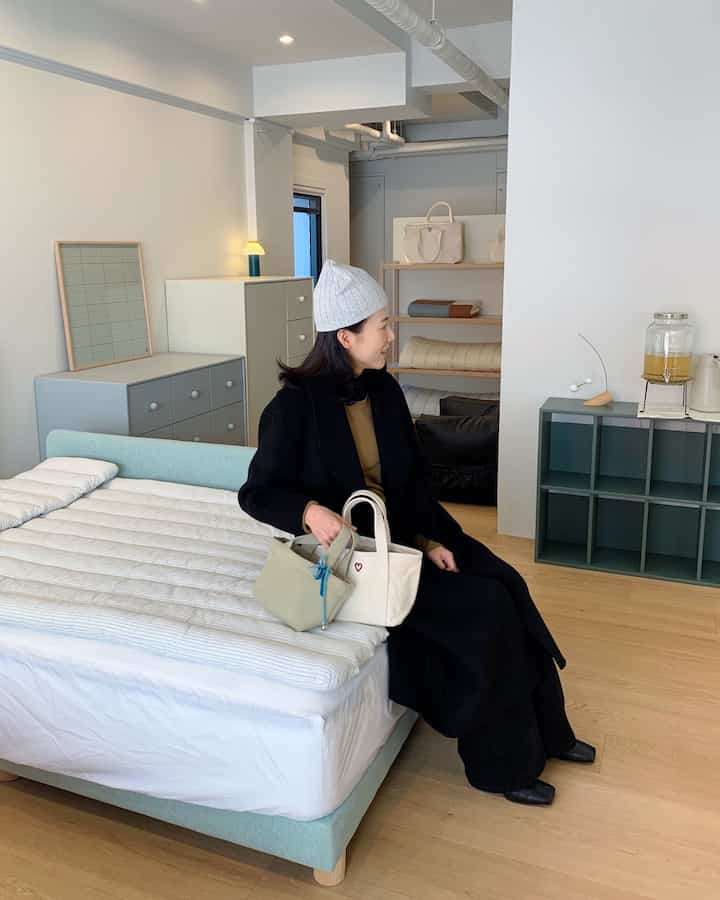 白とナチュラルウッドの色調の寝室、ベッドとチェストが配置されたシンプルで自然な雰囲気のあるインテリア