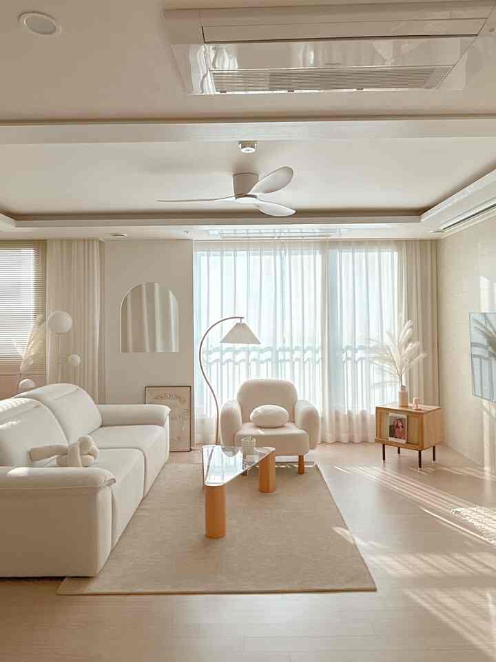 白と木目調の明るいリビング、ソファとアームチェア、コーヒーテーブルが配置されたナチュラルモダンな空間