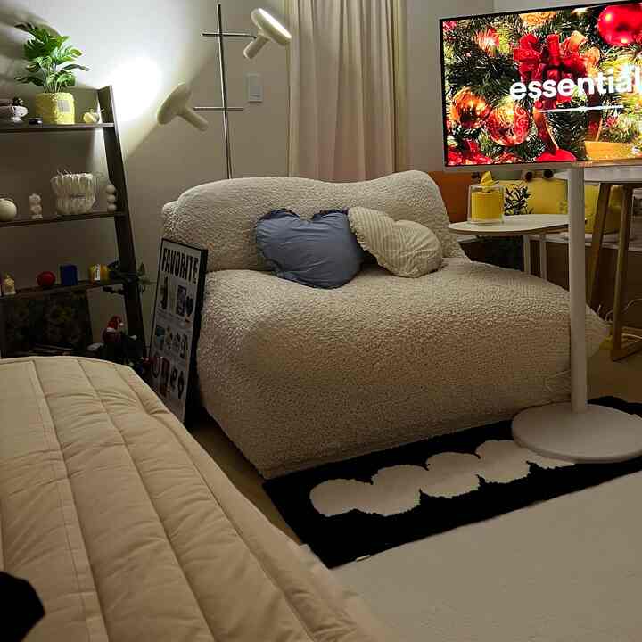 柔らかなホワイトとベージュのトーンの寝室、オフホワイトテクスチャのソファとブラックのラグが調和した居心地の良い空間