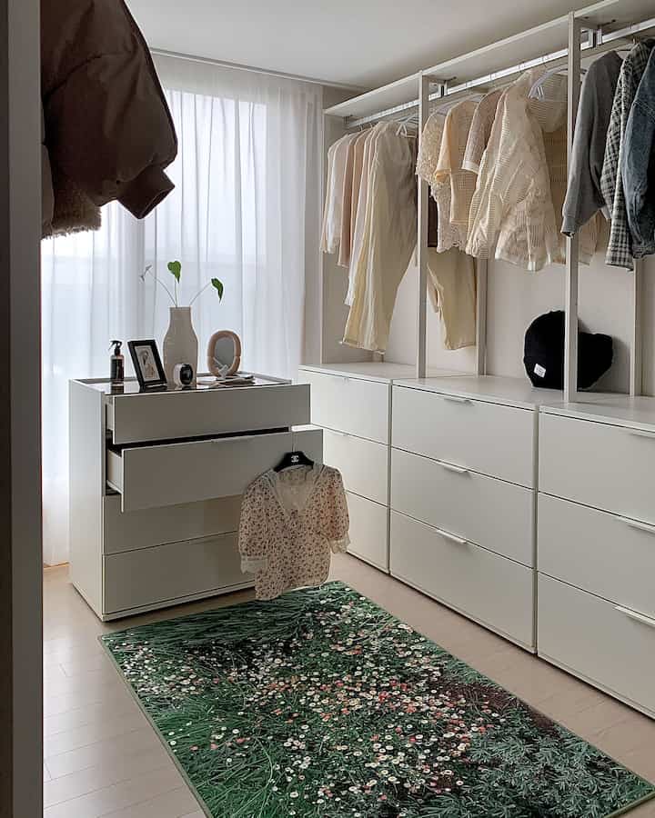 白とベージュの色調のウォークインクローゼット、カスタムシステムハンガーと白の収納が配されたシンプルで落ち着いた雰囲気のインテリア