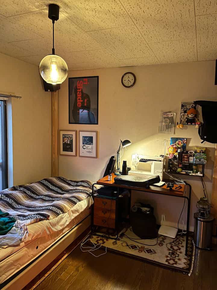 Brown-toned small bedroom featuring a desk with sewing machine and task lamp on the right, creating an atelier atmosphere