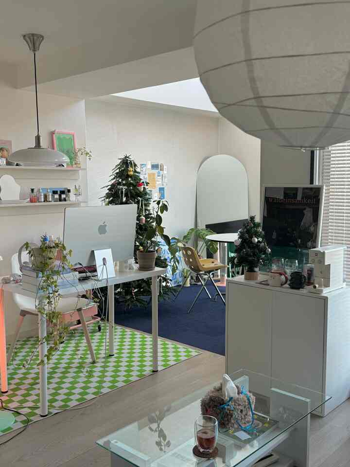 White and blue toned studio apartment featuring desk, Christmas tree, and coffee setup with a cozy modern vibe