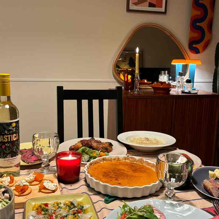 木目調とホワイトカラーが調和したダイニングルーム、テーブルには多彩な料理とワイン、キャンドルが配置された雰囲気のあるホームパーティースペース