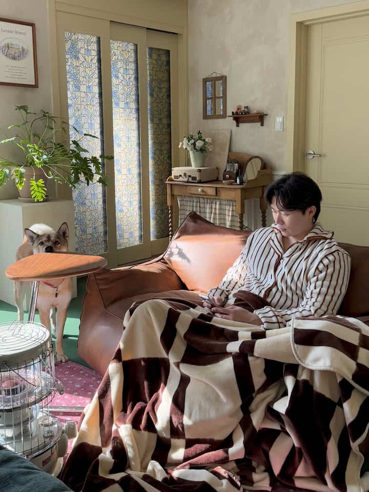 Brown-toned living room featuring a bean bag sofa with large checkered blanket and a dog by the side creating a cozy atmosphere