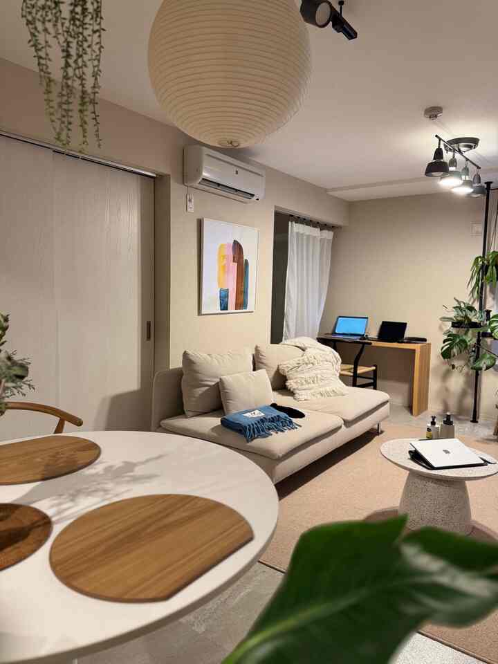 ベージュとホワイトのトーンのリビング、ソファとデスク、自然素材が配置された雰囲気のある在宅勤務空間