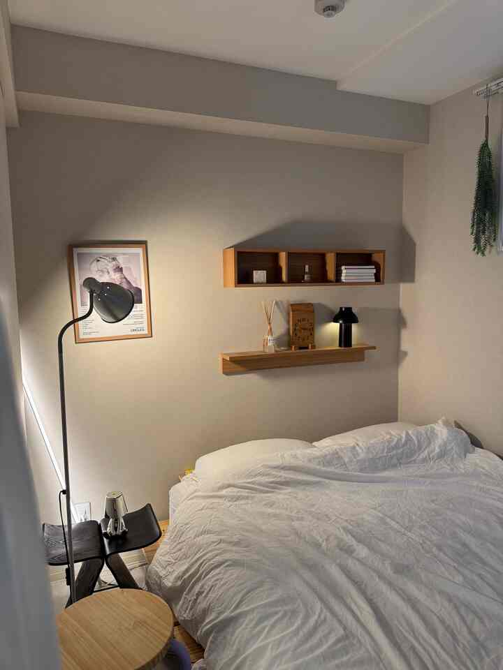 Natural toned bedroom featuring a clean bed and wall-mounted shelves with a calm atmosphere
