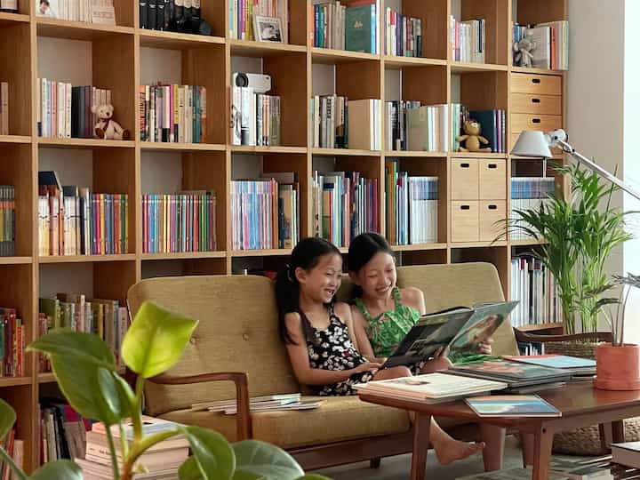 ナチュラルトーンのリビング、大型の本棚とソファが配置された暖かく居心地の良い空間