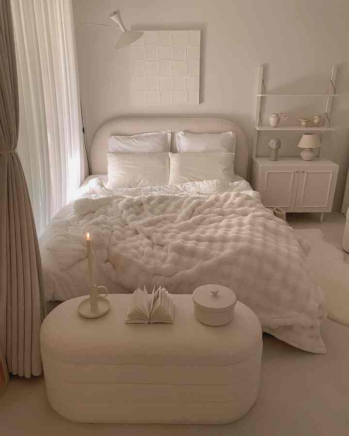 ホワイトとベージュの色調の寝室、柔らかなベッドフレームとブランケットが配置された雰囲気のあるナチュラルモダンな空間