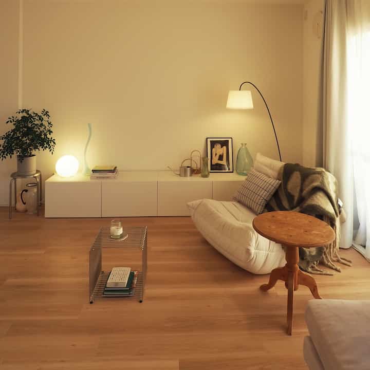 Warm natural and white toned Scandinavian living room featuring a cream sofa and wooden side table creating a cozy atmosphere