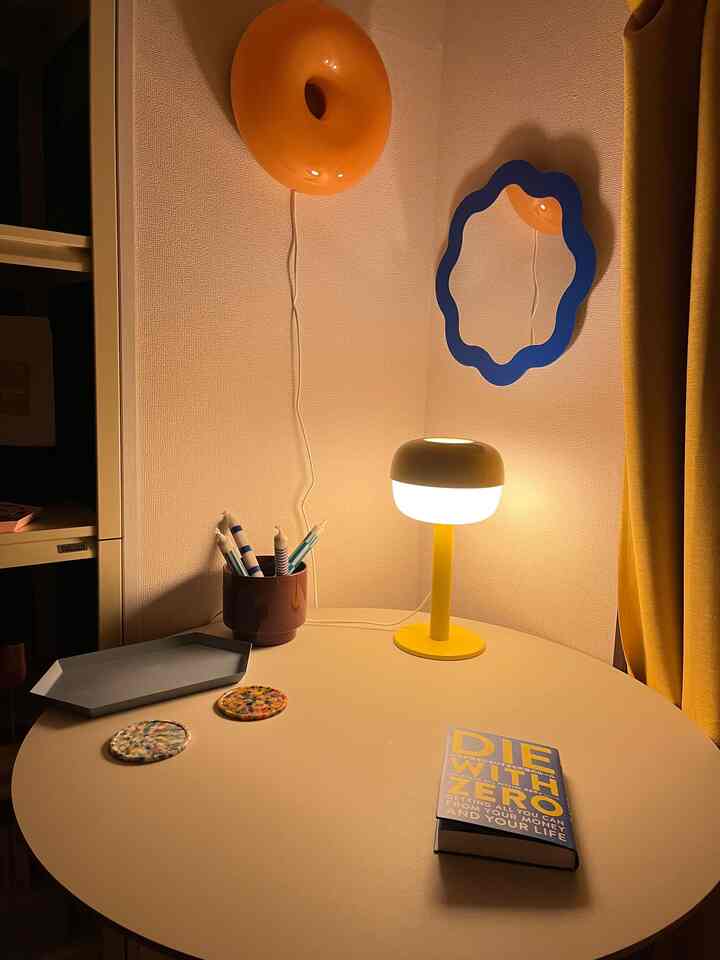 Yellow-toned small workspace featuring a yellow wall sconce, table lamp, and candles creating a warm cozy atmosphere