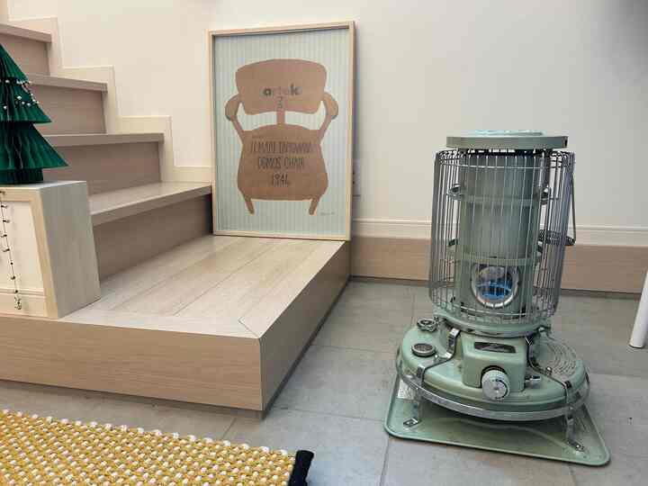 ナチュラルな木目調の玄関、ブルーのストーブと額縁が配置された雰囲気のある空間