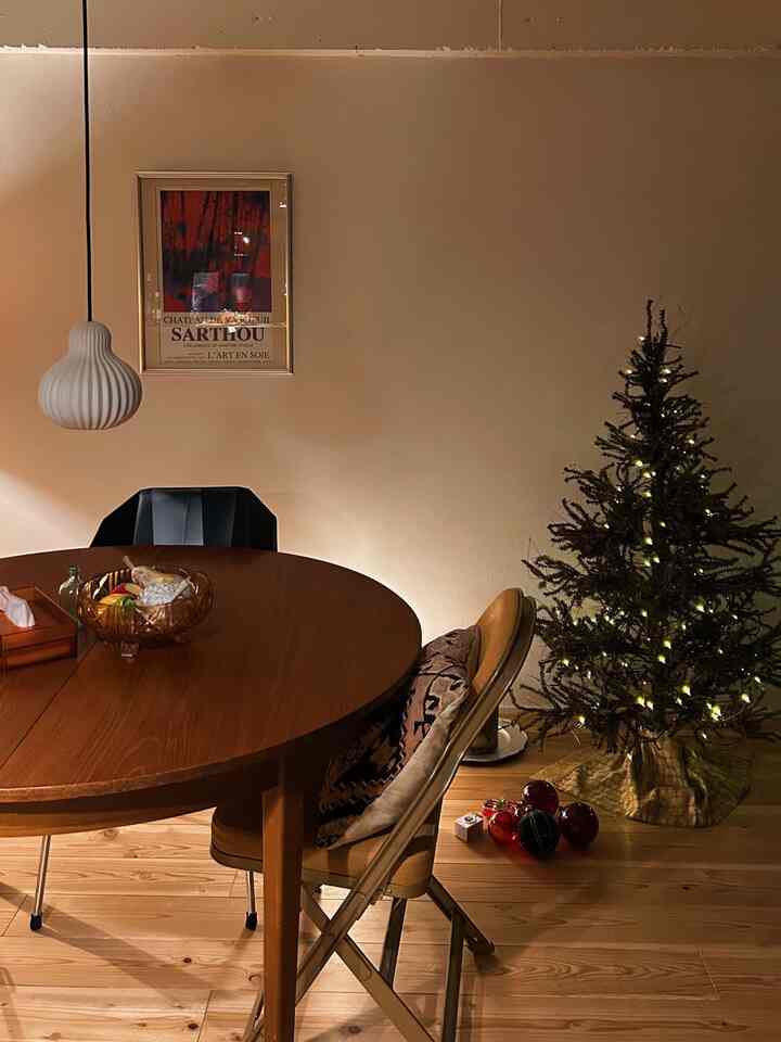 温かみのある木目調のダイニング、丸いダイニングテーブルとクリスマスツリーが配置された雰囲気のある空間