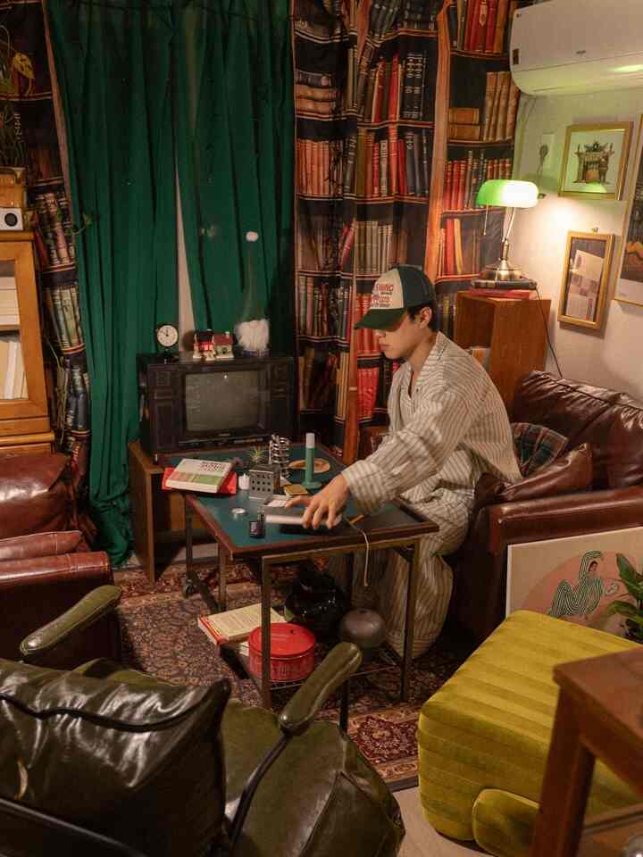 緑と茶色を基調としたレトロなリビング、レザーソファとアームチェアが配置された雰囲気のある空間