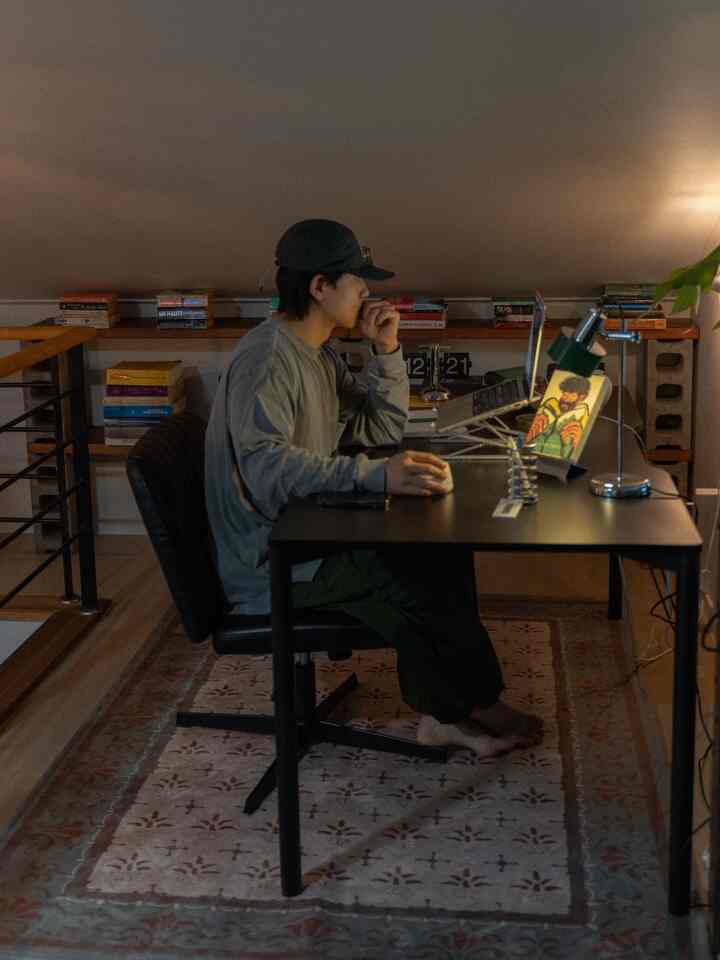 ナチュラルな色調のロフト書斎、黒いデスクと椅子、本棚が配置された落ち着いた雰囲気のインテリア