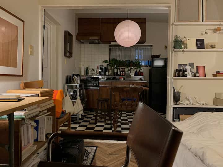A cozy studio apartment kitchen and living space featuring natural brown and white tones with vintage elements