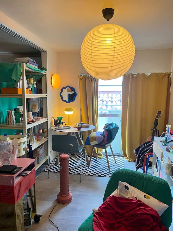 Cozy small room with yellow lighting and dining table, featuring a green armchair and checkered rug in a colorful interior