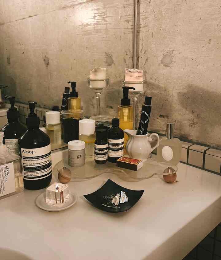 Natural toned bathroom countertop with various skincare products and candles creating a calm atmosphere