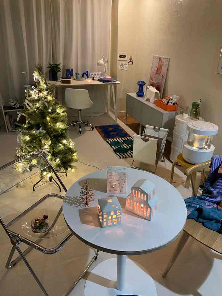 White and wood tone 1DK living space featuring a lit Christmas tree and ceramic candle holders creating a cozy atmosphere