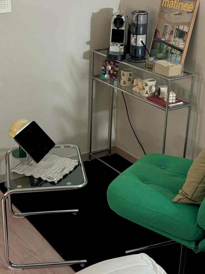 緑色のソファとシルバーの金属家具が配置されたワンルーム空間、ホームカフェ要素が際立つ雰囲気のあるインテリア