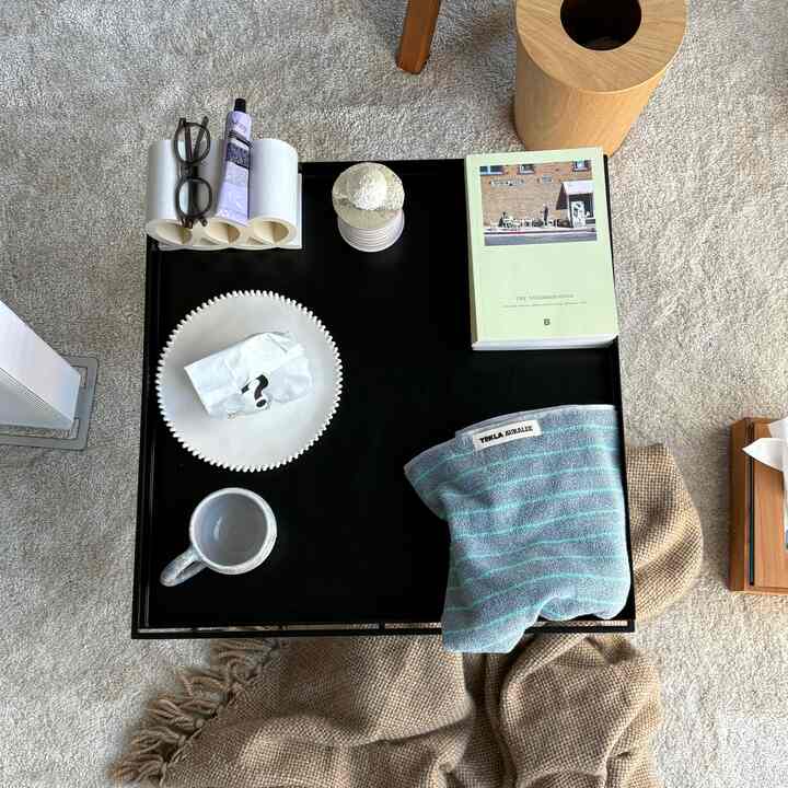 ベージュと黒のトーンのリビング、黒いコーヒーテーブルの上にマグカップと本が配置された雰囲気のあるインテリア