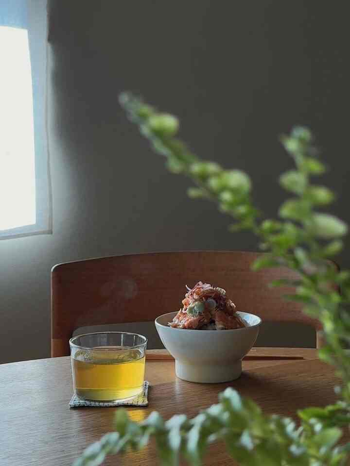 自然な木目調のダイニングルーム、蒸気の立つ器とお茶のグラスが配置された暖かい雰囲気のあるインテリア