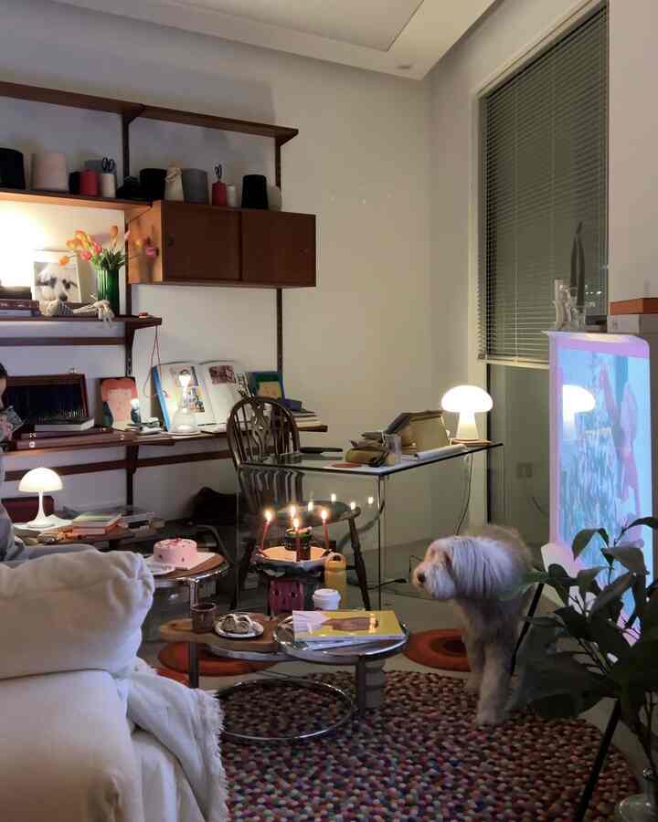 暖かい照明と白いソファ、デスク、ペットの犬がいるモダンなリビングルーム