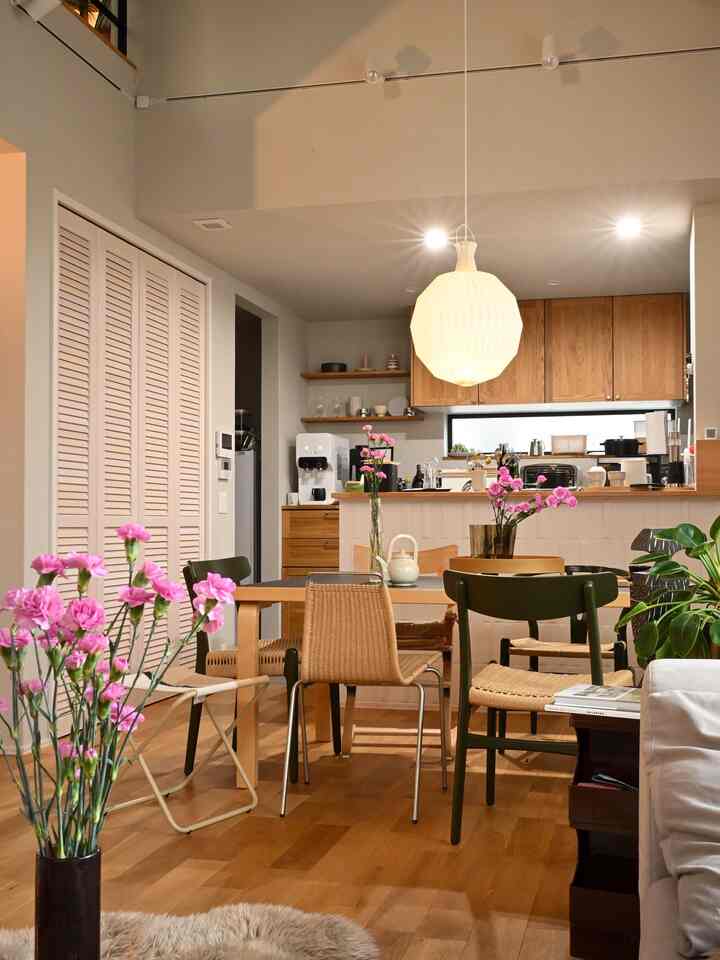 ナチュラルな木目調とピンクの花瓶が調和する北欧風のダイニングルーム、ミッドセンチュリーモダンの家具が配置された雰囲気のあるインテリア