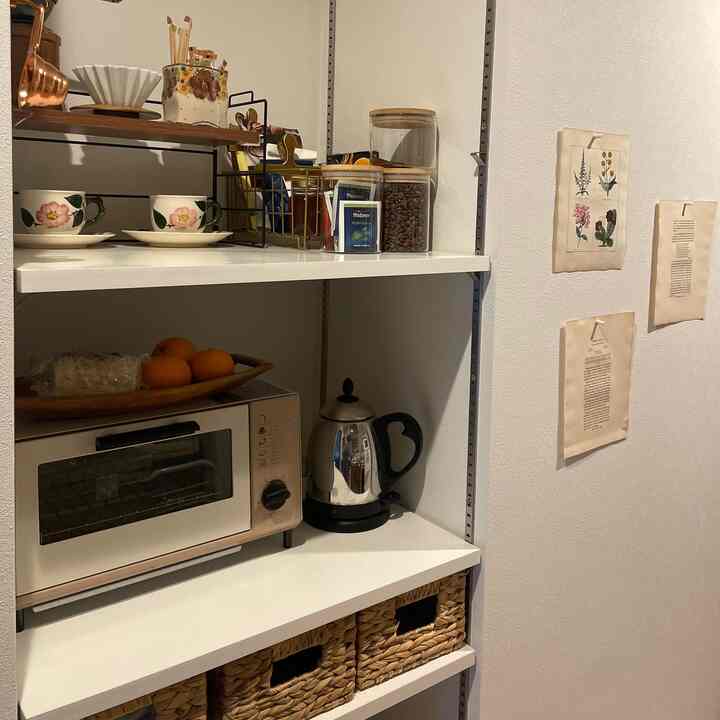 白とナチュラルカラーのキッチン棚にコーヒー用品と収納バスケットが配置された、清潔感あるおうちカフェの雰囲気のあるインテリア