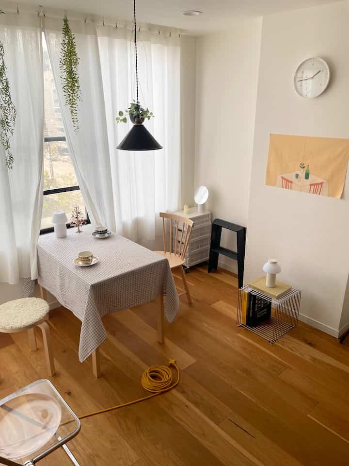 白い壁と木目調の床が調和する北欧スタイルのダイニング、チェック柄のテーブルクロスと木製の椅子が配置された印象的な空間