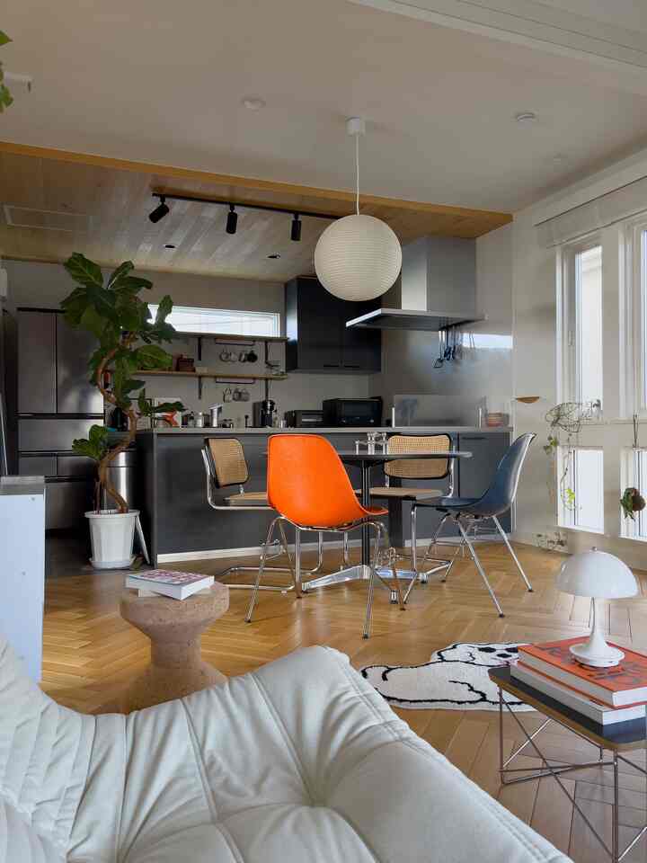 白と木目調が調和したモダンなダイニング、オレンジのダイニングチェアがアクセントの温かみのある空間