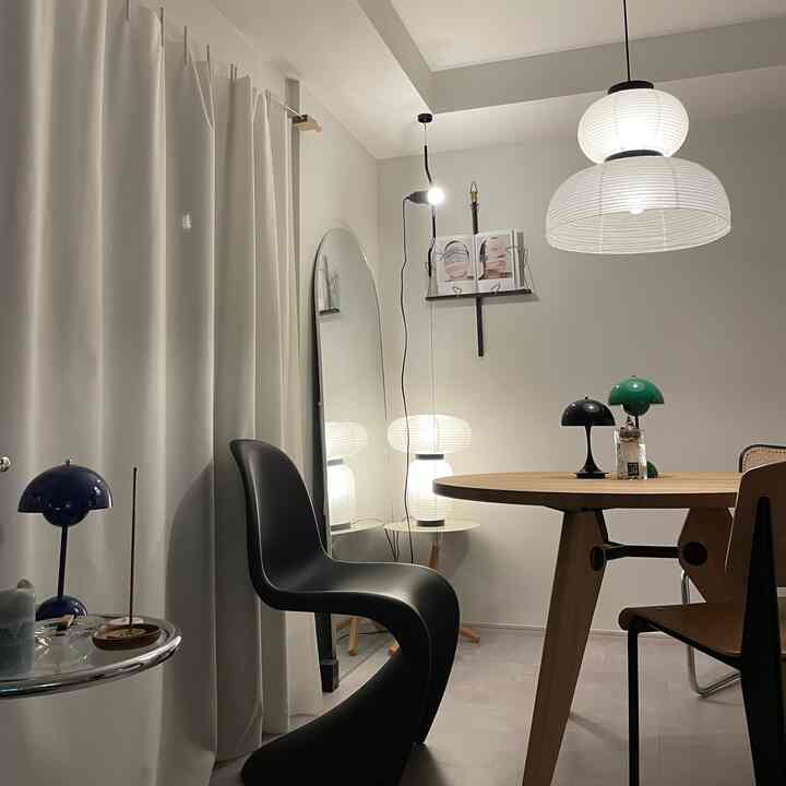 白と木目調が調和したモダンなダイニング、丸いテーブルと多彩な照明が配置された雰囲気のある空間