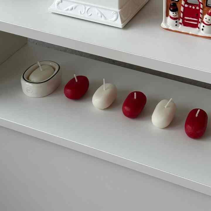 Cozy space featuring neatly arranged red and white candles on a white shelf