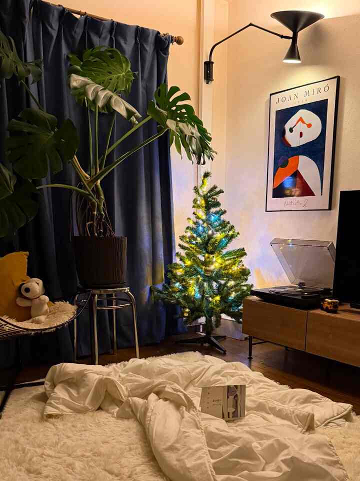 ナチュラルな色調のリビング、モンステラの植物と暖かい照明のクリスマスツリーが配置された雰囲気あるインテリア