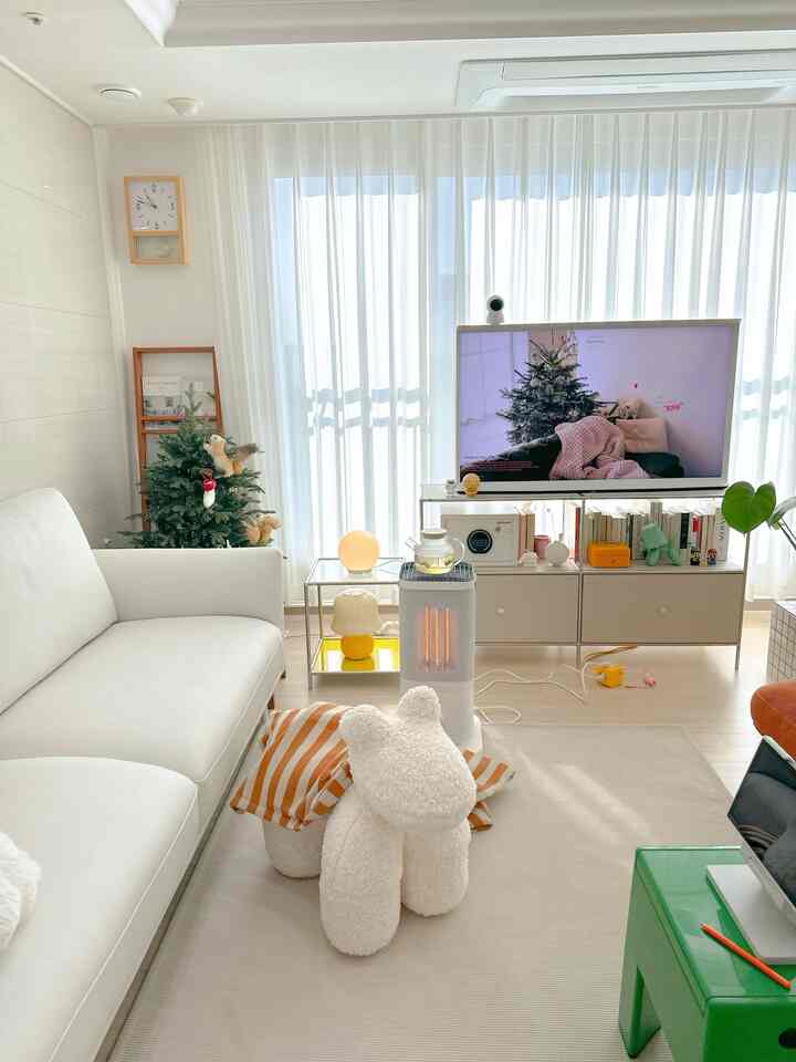 Bright white toned living room featuring a white sofa and sheer curtains, creating a cozy and clean atmosphere