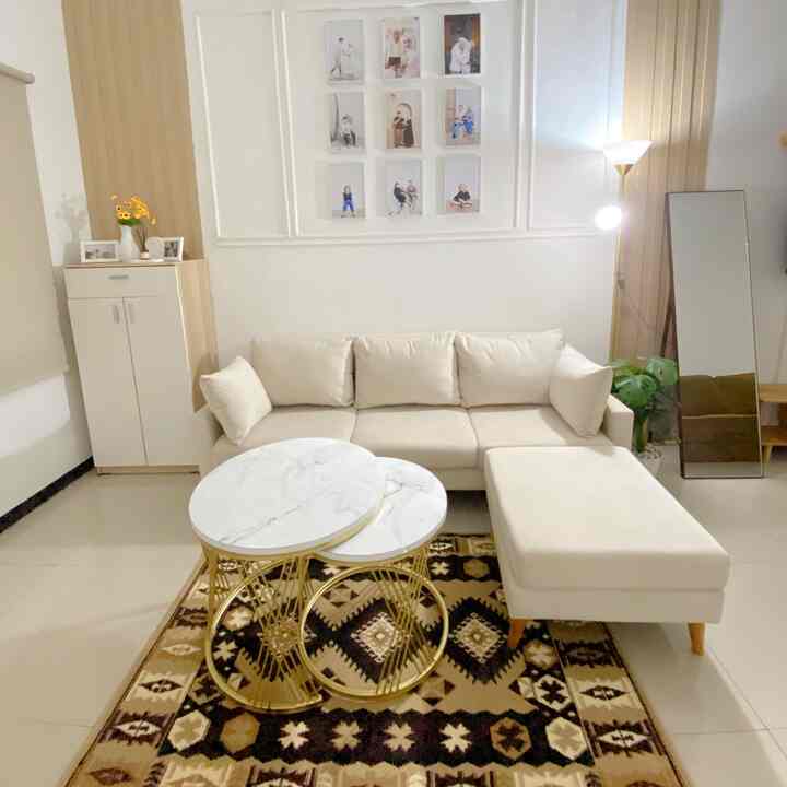 Bright white and brown toned living room featuring a sectional sofa and marble coffee tables arranged neatly with a cozy atmosphere