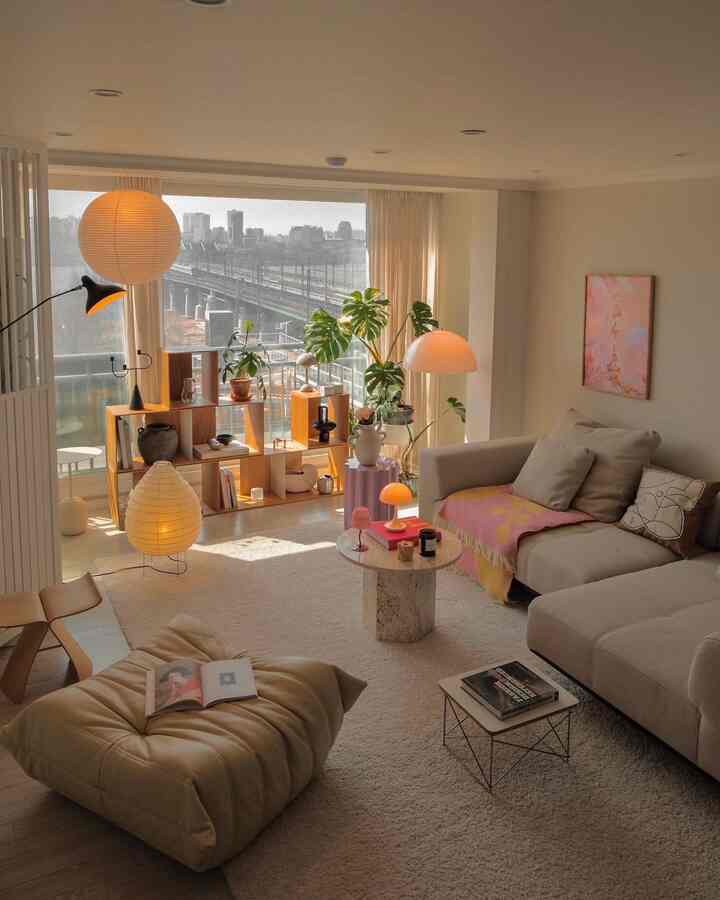 温かみのあるベージュと木目調のリビング、広いソファとモジュラーシェルフ、フロアランプが調和した印象的な空間