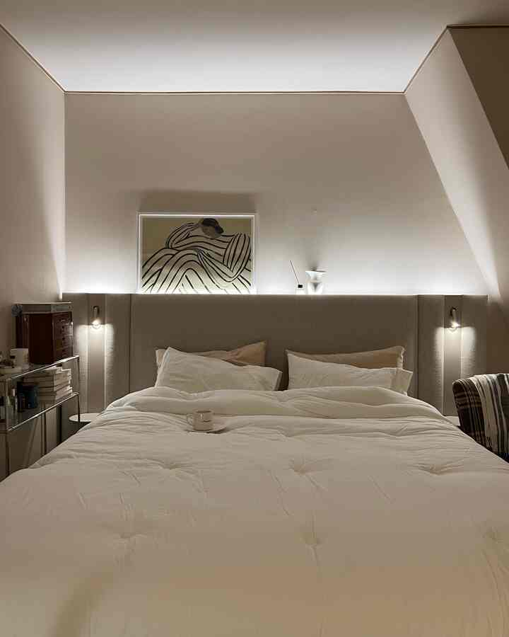 ベージュと白の色調の寝室、中央に大きなベッドが配置され、両側に壁照明がある雰囲気のあるナチュラルモダンなインテリア