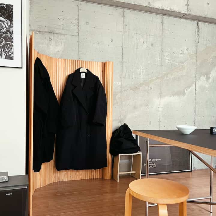 ウッドトーンとブラックが調和するインダストリアルスタイルのコーナー収納とスツールが置かれたリビング空間