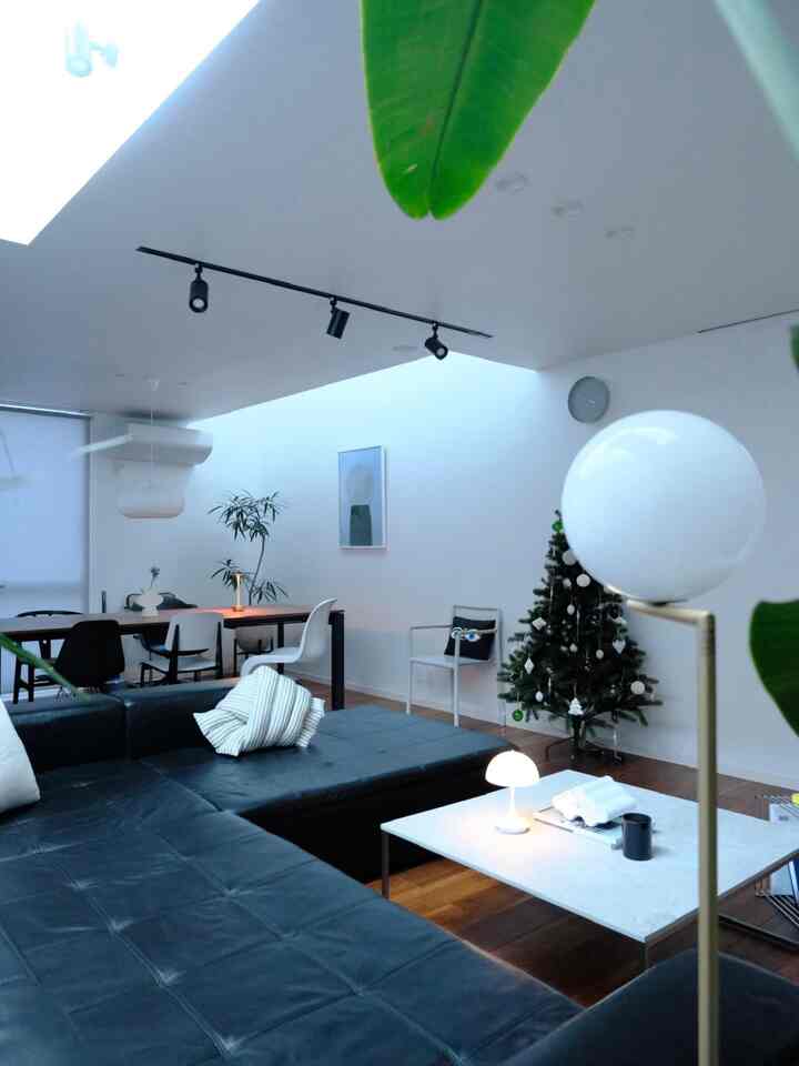 白と黒の調和が取れたリビング、広いソファとクリスマスツリーが配置されたシンプルでモダンなインテリア