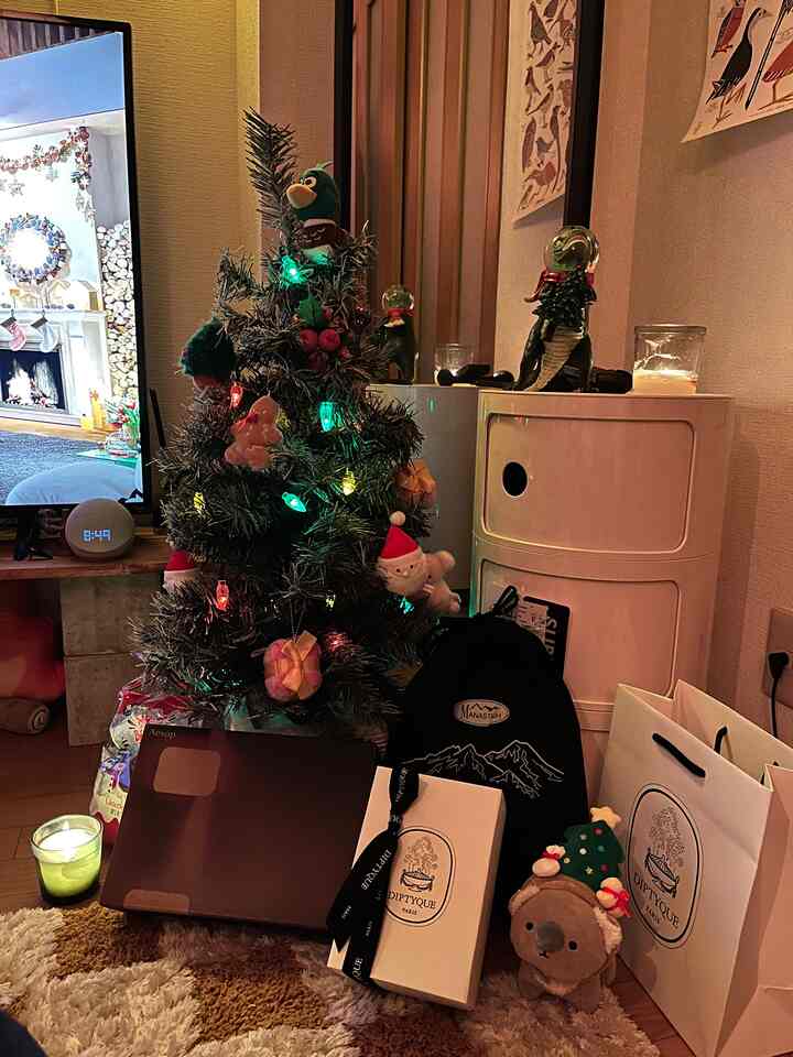 A cozy small living room in brown and white tones featuring a decorated Christmas tree, gift boxes, and a lit candle