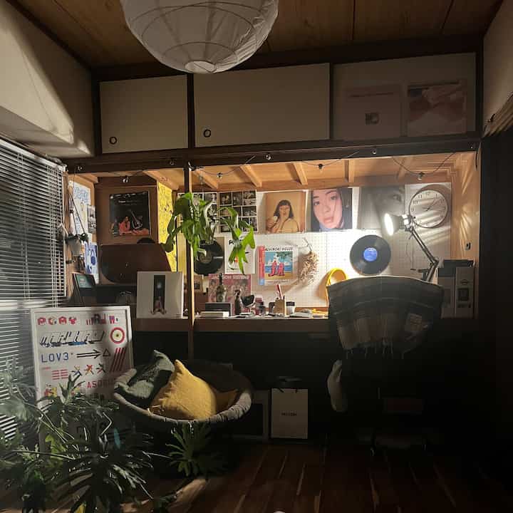 温かみのある木目調と植物、レコード、時計が配置された居心地の良い作業スペース