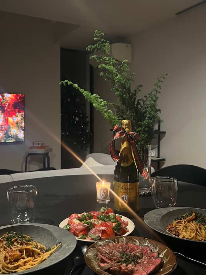 Living room with a black round table set with Christmas-themed food and a candle, featuring a white sofa and plants