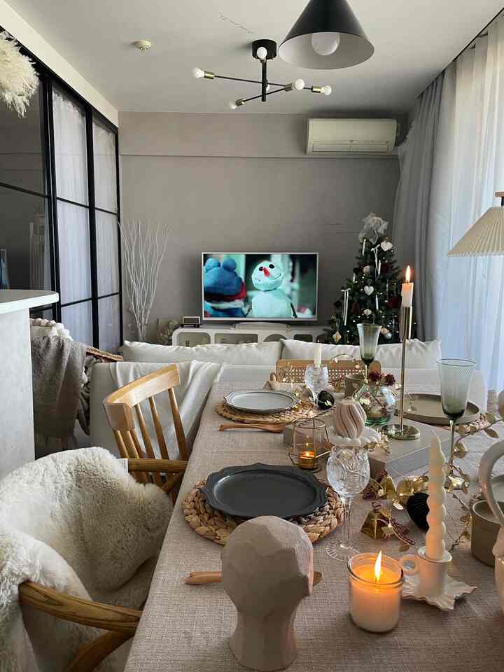 ナチュラルなベージュと白を基調とした狭いリビング、ダイニングテーブルとコーナーソファが配置された雰囲気のあるクリスマスインテリア