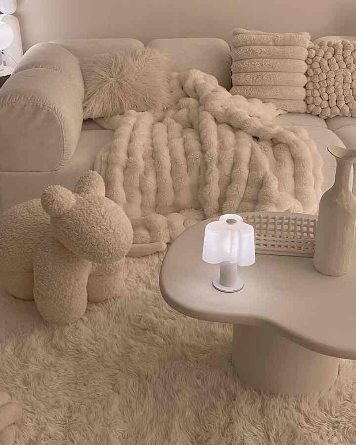 ベージュ調のリビング、ふわふわのラグとソファ、ブランケットが温かみのある雰囲気のインテリア